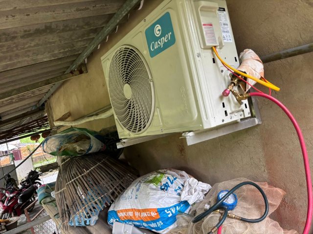 Dàn nóng đặt trên giá treo tường, đường ống gas và dây điện đã được bọc bảo ôn cẩn thận. Kỹ thuật viên cũng đang kiểm tra áp suất gas bằng đồng hồ nạp gas.